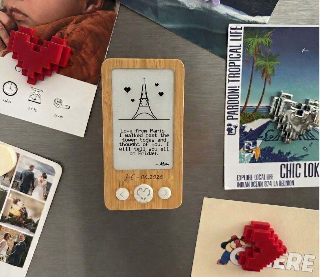 Bamboo e-ink magnet on a fridge door, between photos and postcards, showing a drawing and a note